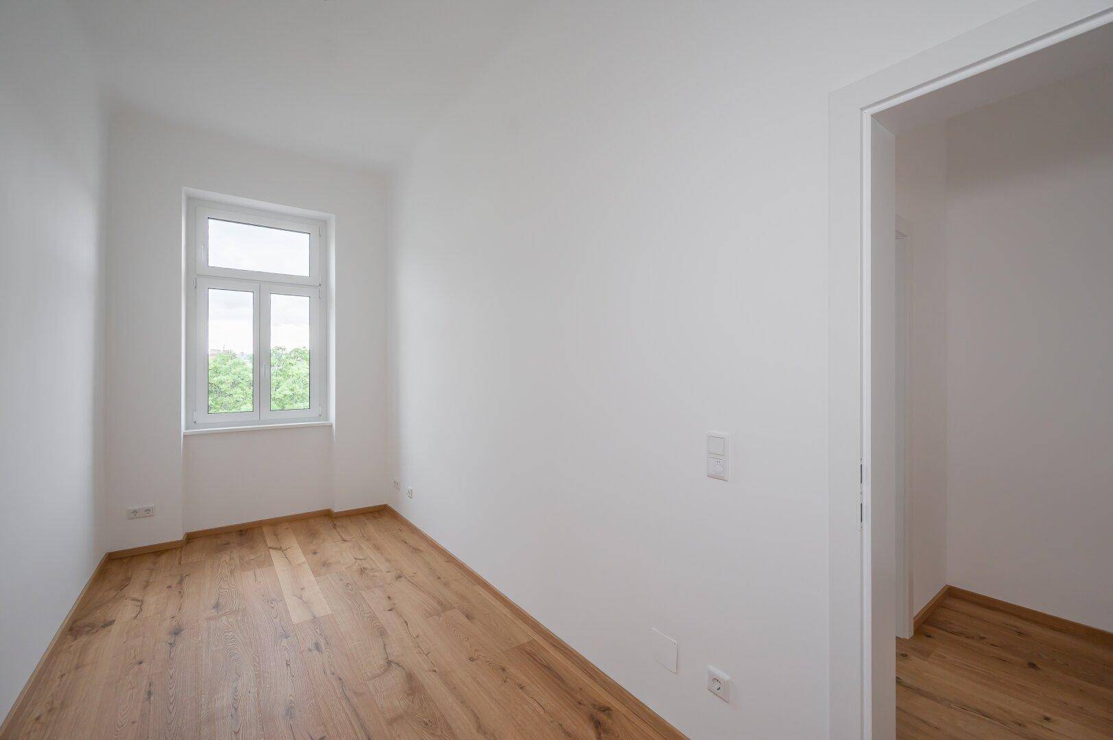 Kleines, helles Zimmer mit Holzboden und Fenster, geeignet als Kinderzimmer oder Büro.
