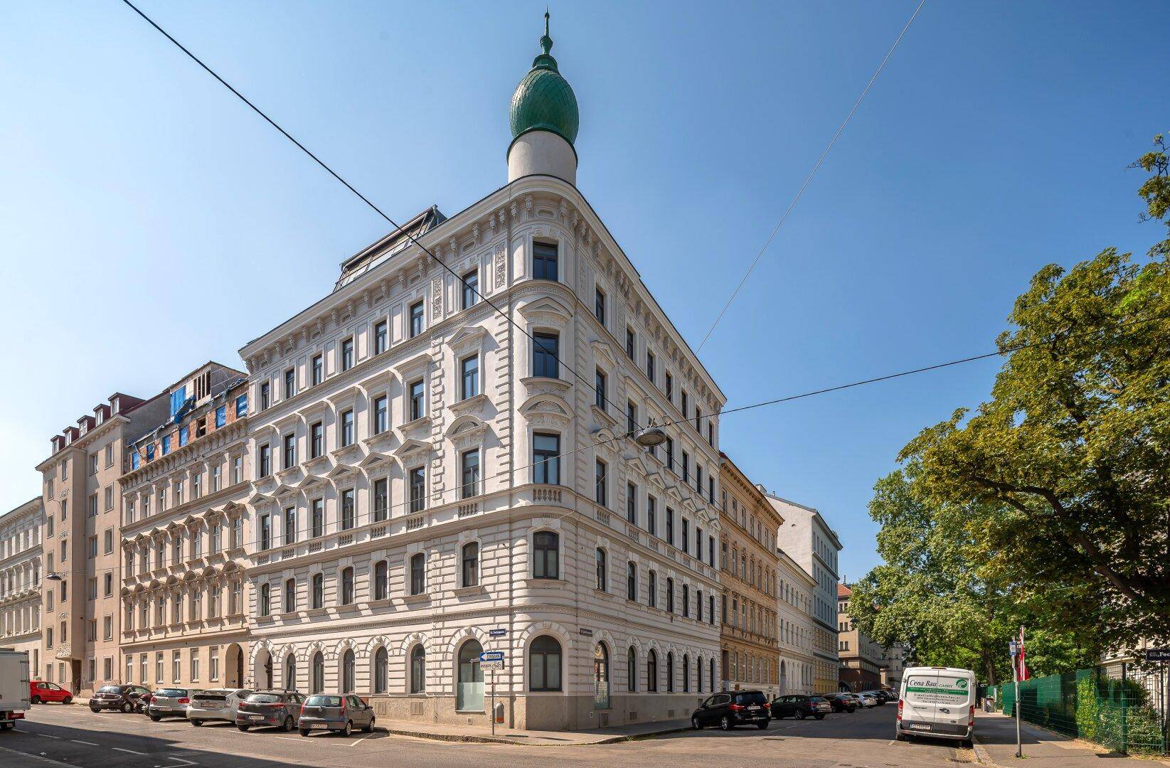 Elegantes Eckgebäude mit markantem Turm und klassischer Architektur in urbaner Umgebung.