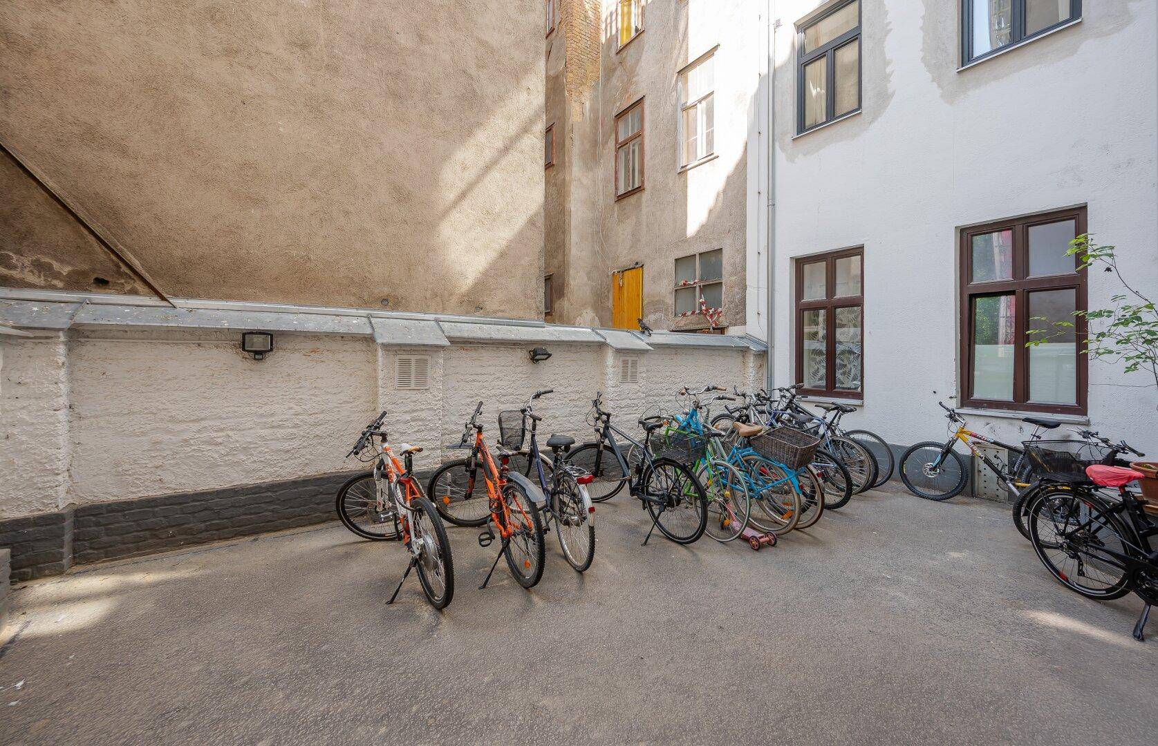 Innenhof mit Fahrradabstellplätzen und alten Gebäudefassaden im Hintergrund.