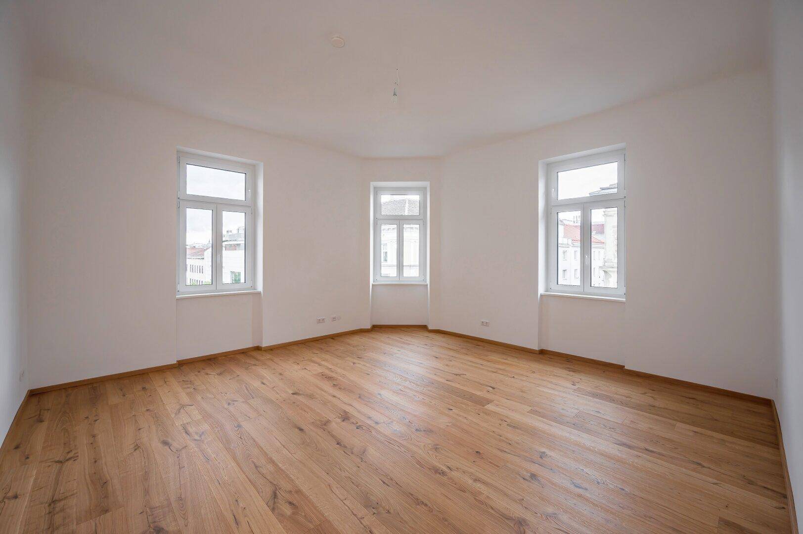 Geräumiger, leerer Raum mit Holzboden und vielen Fenstern, bereit zur individuellen Gestaltung.