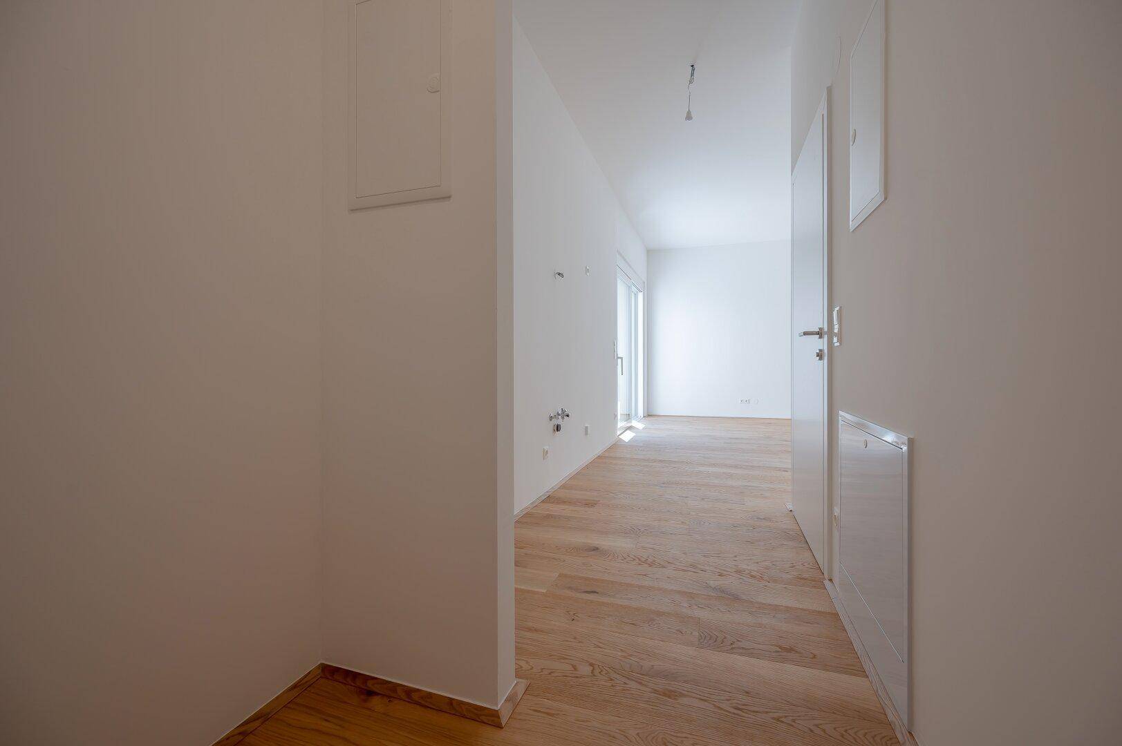 Heller Flur mit Holzboden und Zugang zu weiteren Zimmern, ausgestattet mit modernen Türen.