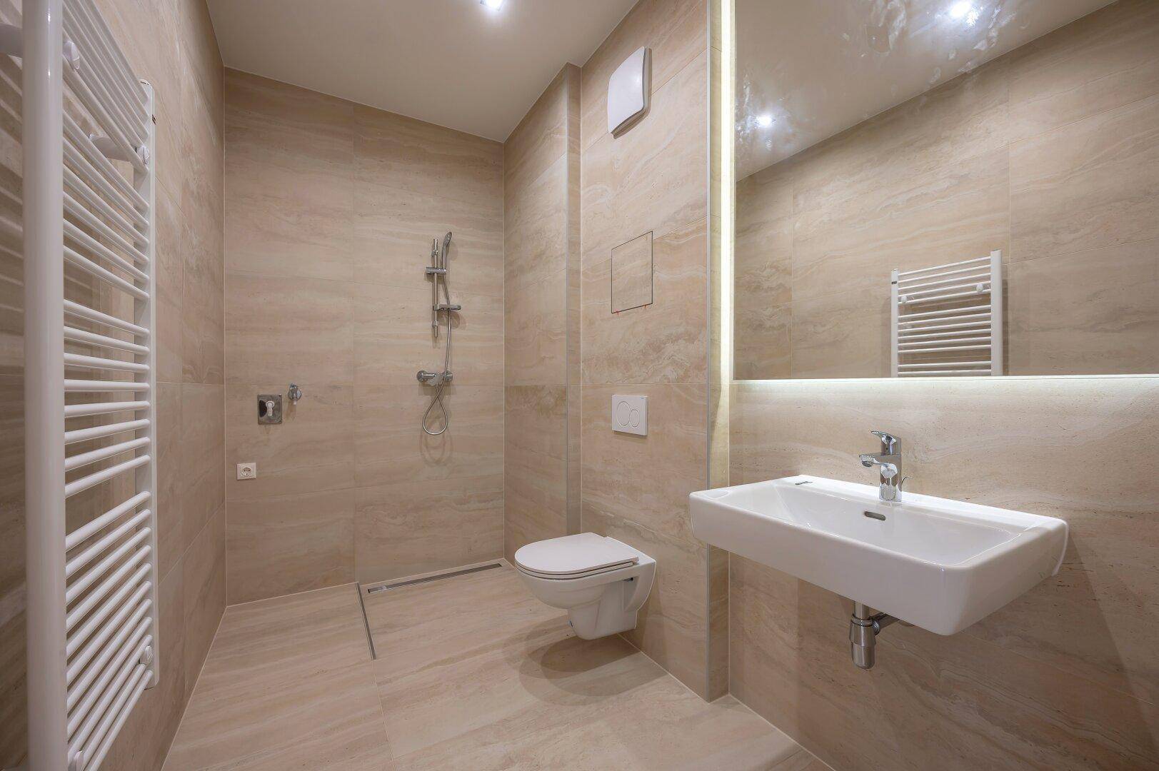 Modernes Badezimmer mit beigefarbenen Fliesen, ebenerdiger Dusche und beheiztem Handtuchhalter.