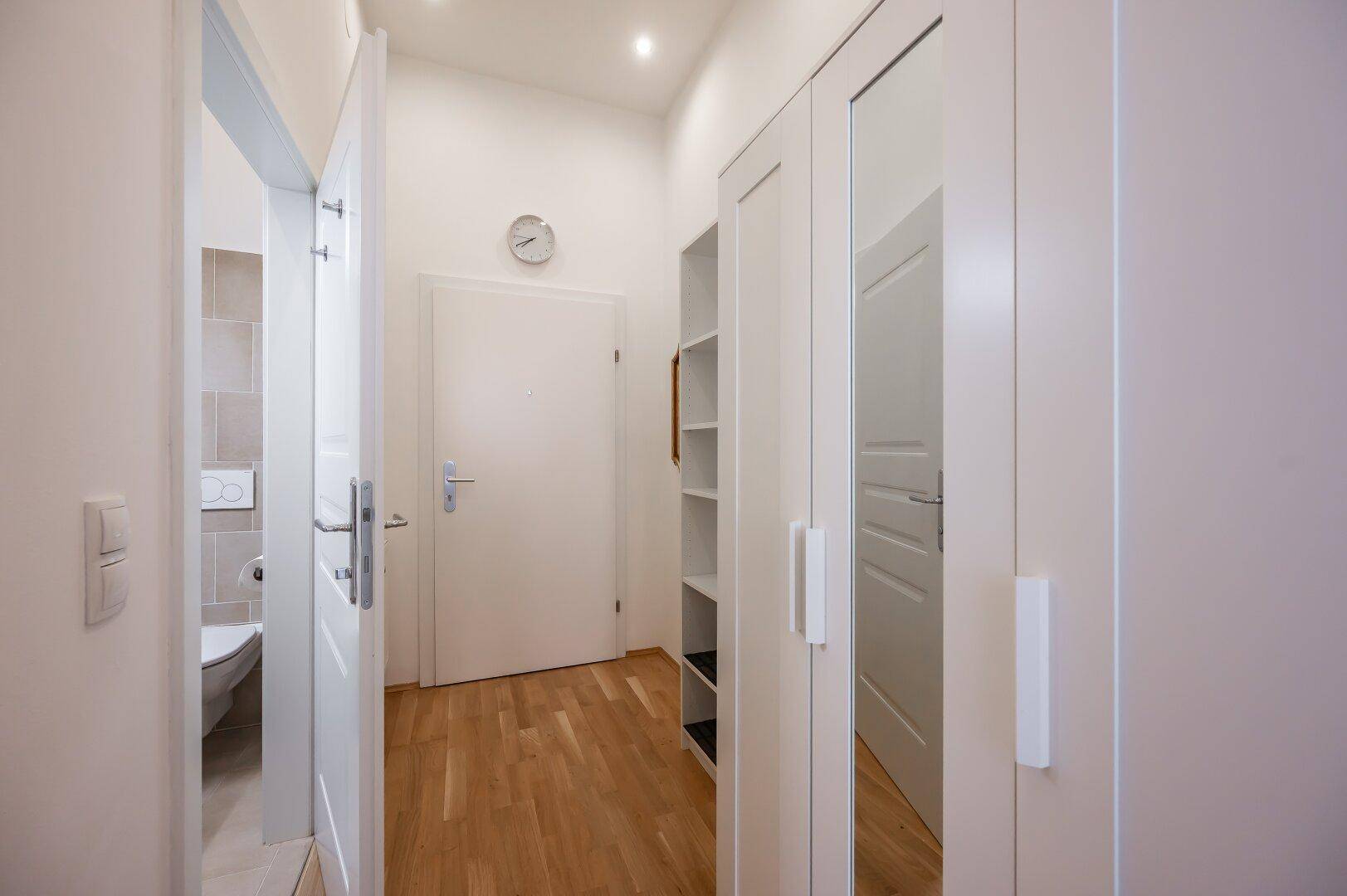 Heller Flur mit Einbauschrank und Zugang zu einem modernen Badezimmer.