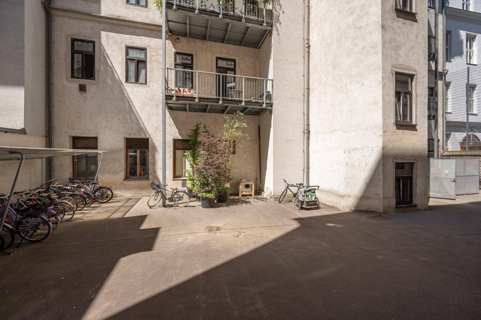 Hinterhofbereich eines Gebäudes mit Fahrradstellplätzen und Balkonen.