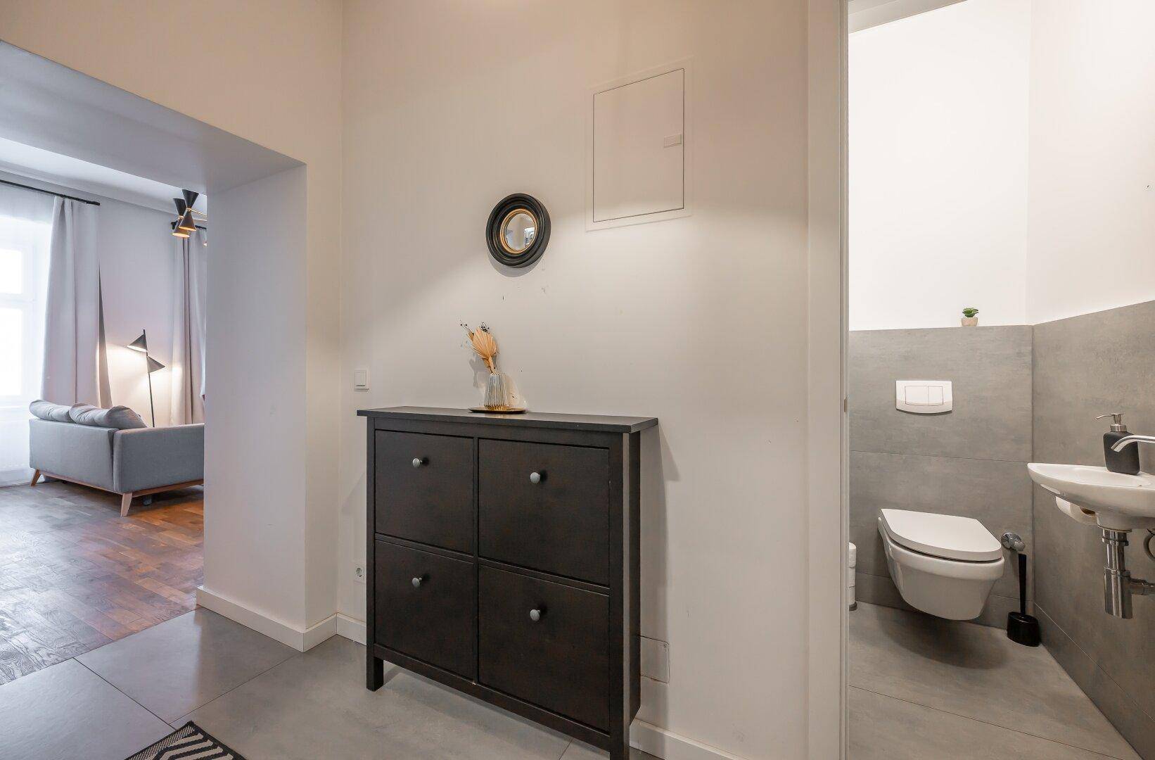 Kleines Gäste-WC mit Wand-WC, Waschbecken und modernen grauen Fliesen.