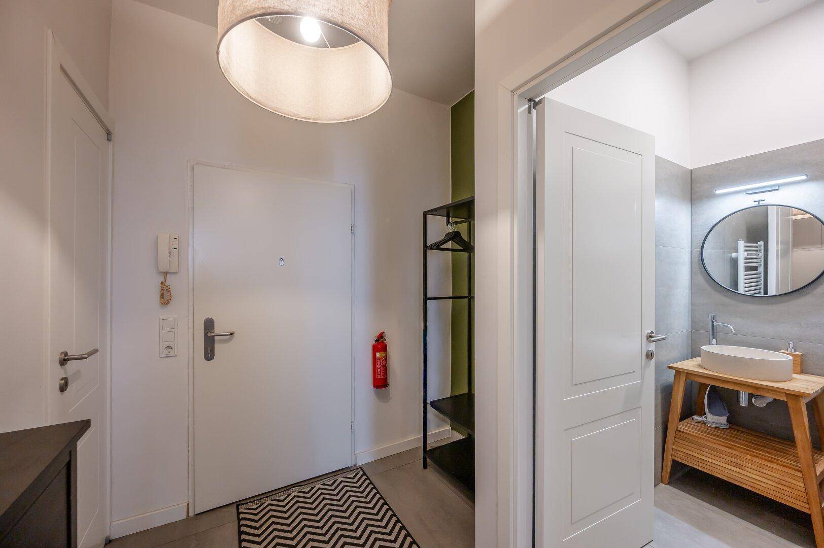 Eingangsbereich mit Schuhschrank und Zugang zu einem modernen Badezimmer.