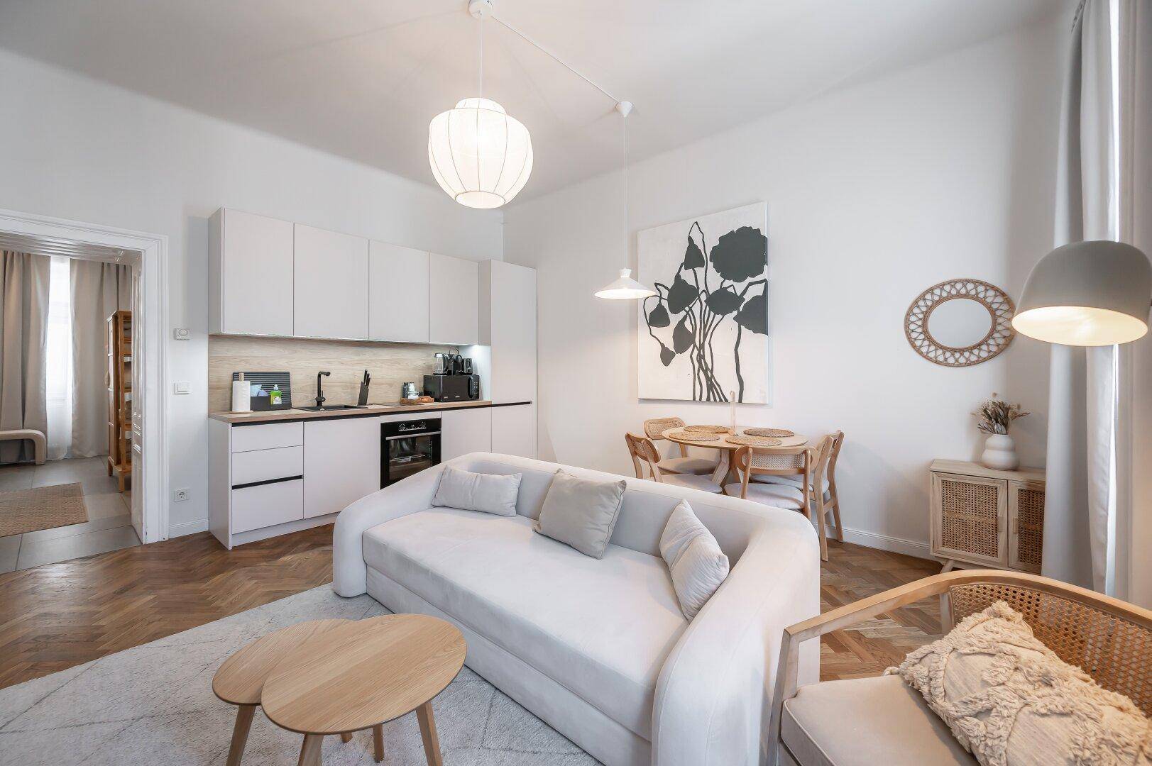 Offener Wohnbereich mit integrierter moderner Küche, hellem Sofa und Esstisch, perfekt für geselliges Beisammensein.