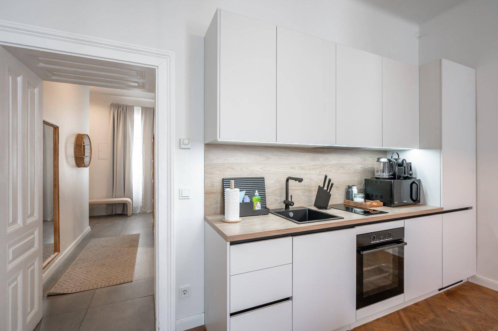 Moderne Einbauküche mit weißen Schränken, Holz-Arbeitsplatte und integrierten Geräten.