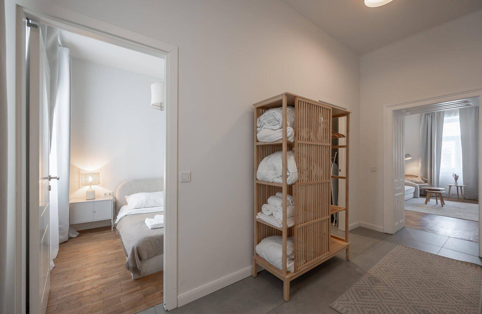 Heller Flur mit Holzregal und Zugang zu zwei Schlafzimmern, bietet praktischen Stauraum.
