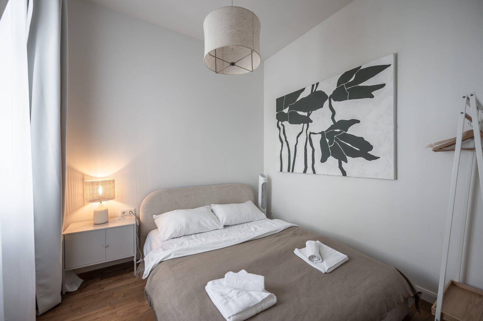 Gemütliches Schlafzimmer mit Doppelbett, Nachttisch und modernem Kunstwerk an der Wand.