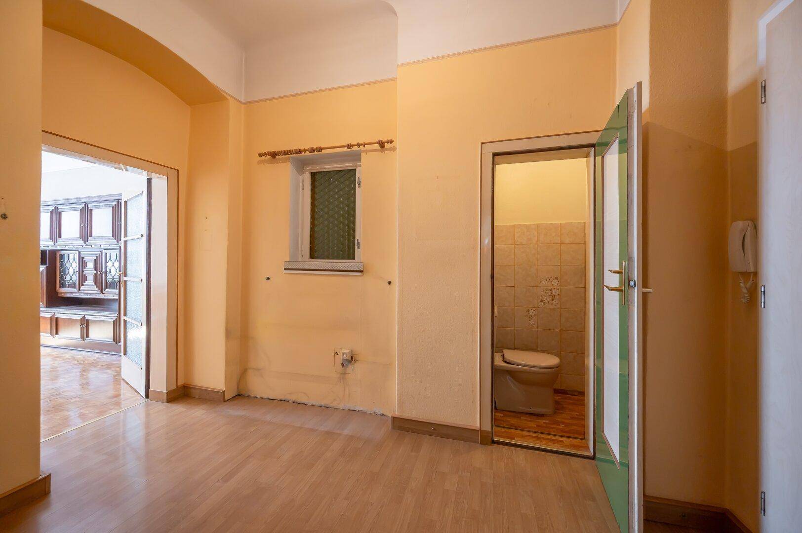 Flur mit Holzboden und Zugang zu einem separaten WC, bietet einen praktischen Durchgangsbereich.