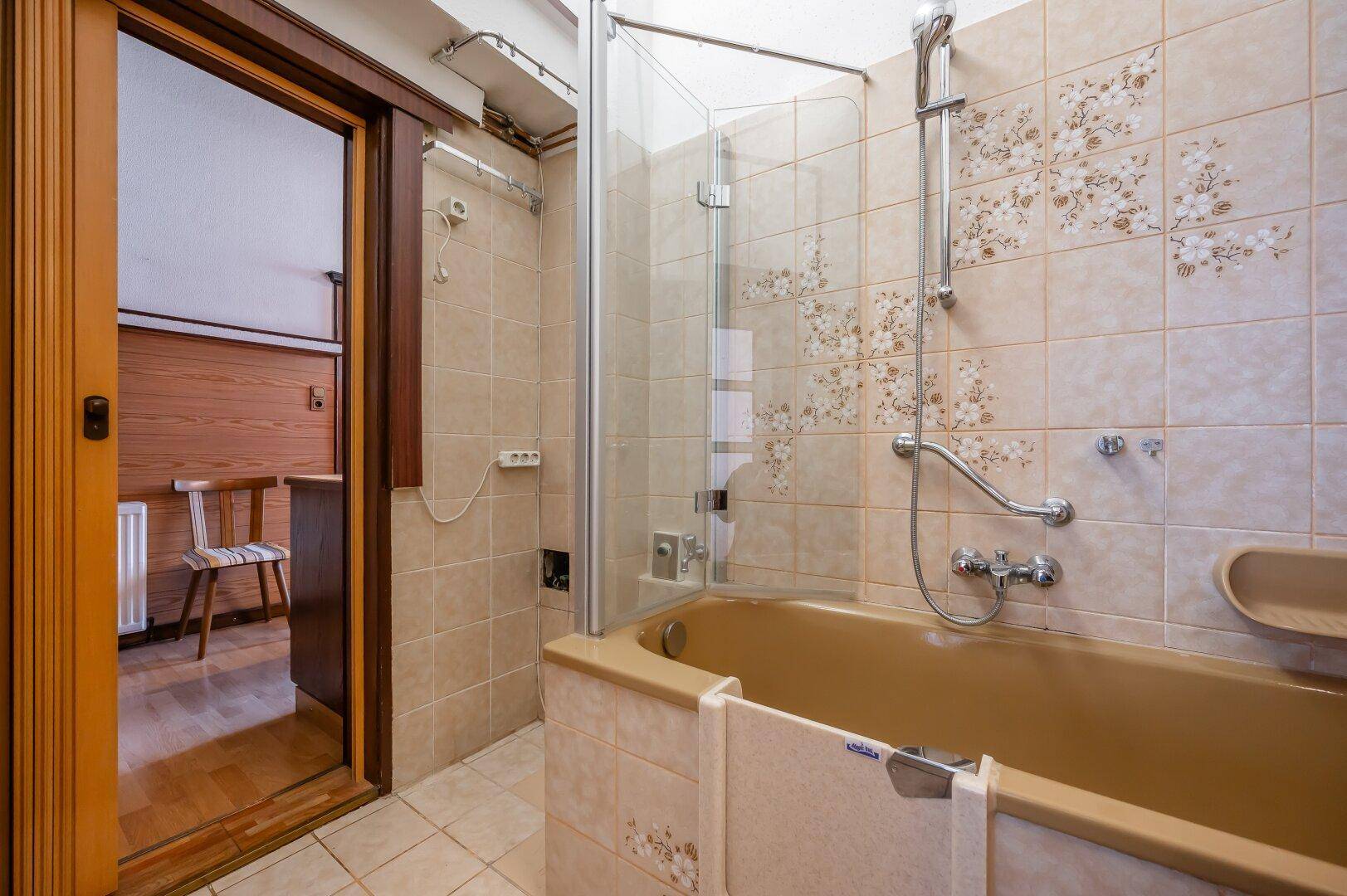 Funktionales Badezimmer mit Badewanne und Duschwand, bereit für eine umfassende Modernisierung.