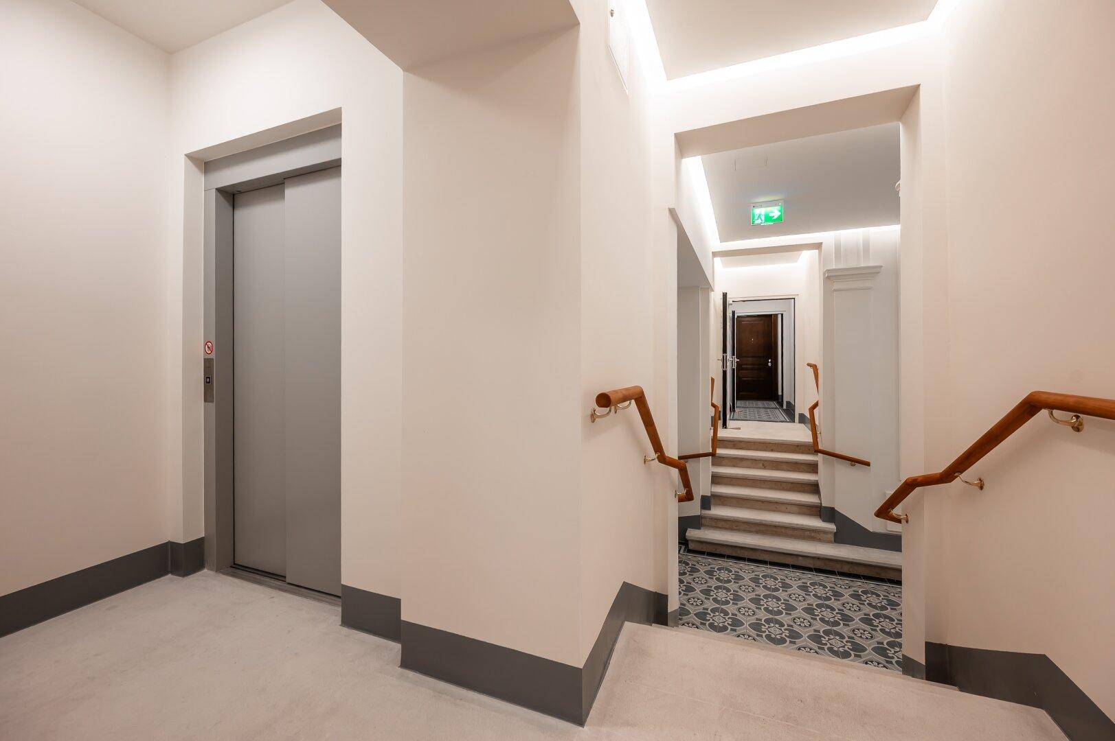 Heller Flur im Treppenhaus mit modernem Aufzug und Zugang zu den Wohnungen.