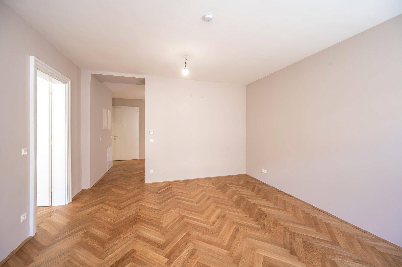 Heller Flur mit Fischgrätparkettboden und Zugang zu weiteren Räumen, modern und gepflegt.