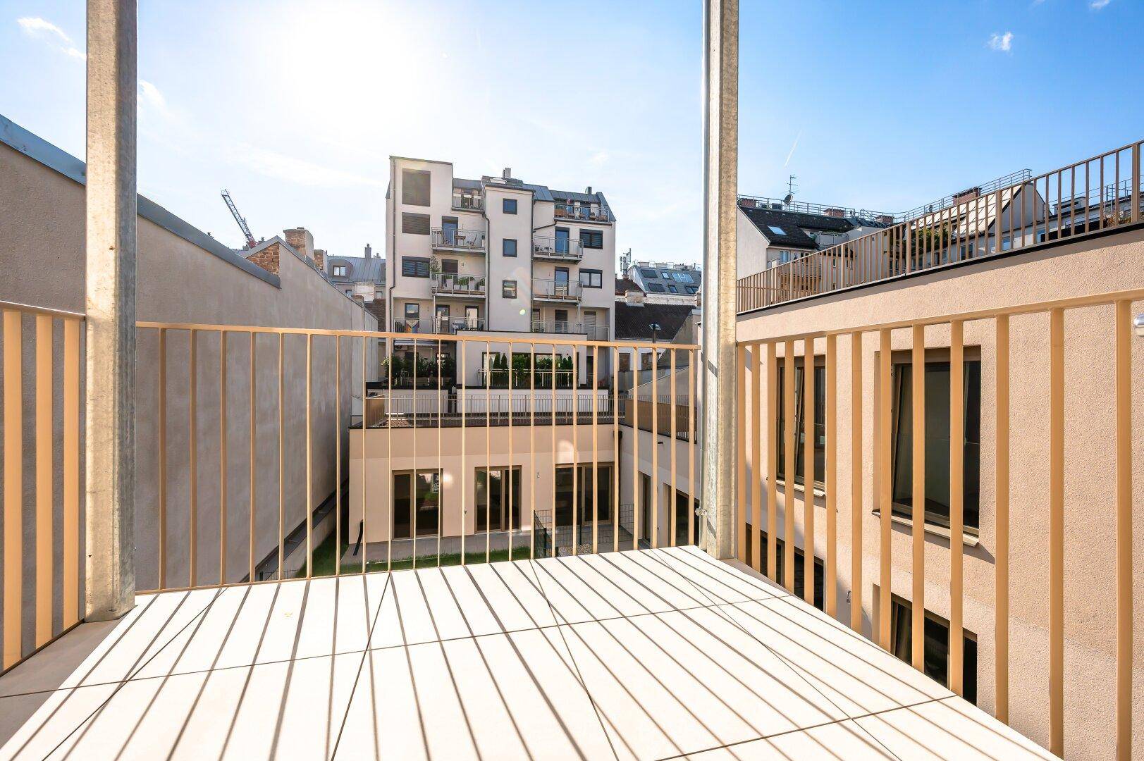 Heller Balkon mit Holzboden und Blick auf die umliegenden Gebäude.