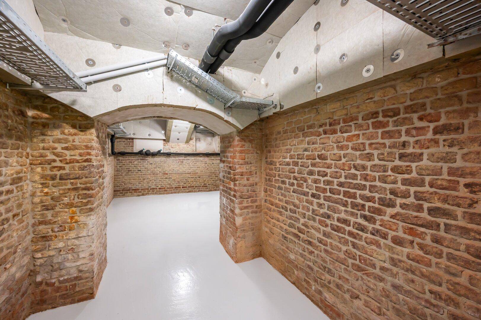 Historischer Kellerraum mit Ziegelwänden und moderner Deckeninstallation.