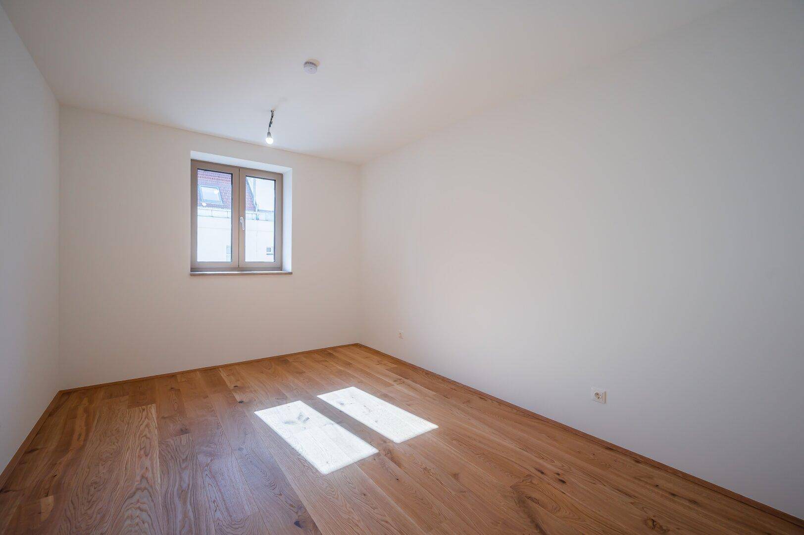 Ruhiges Schlafzimmer mit Holzboden und weiß gestrichenen Wänden, ideal für Erholung.