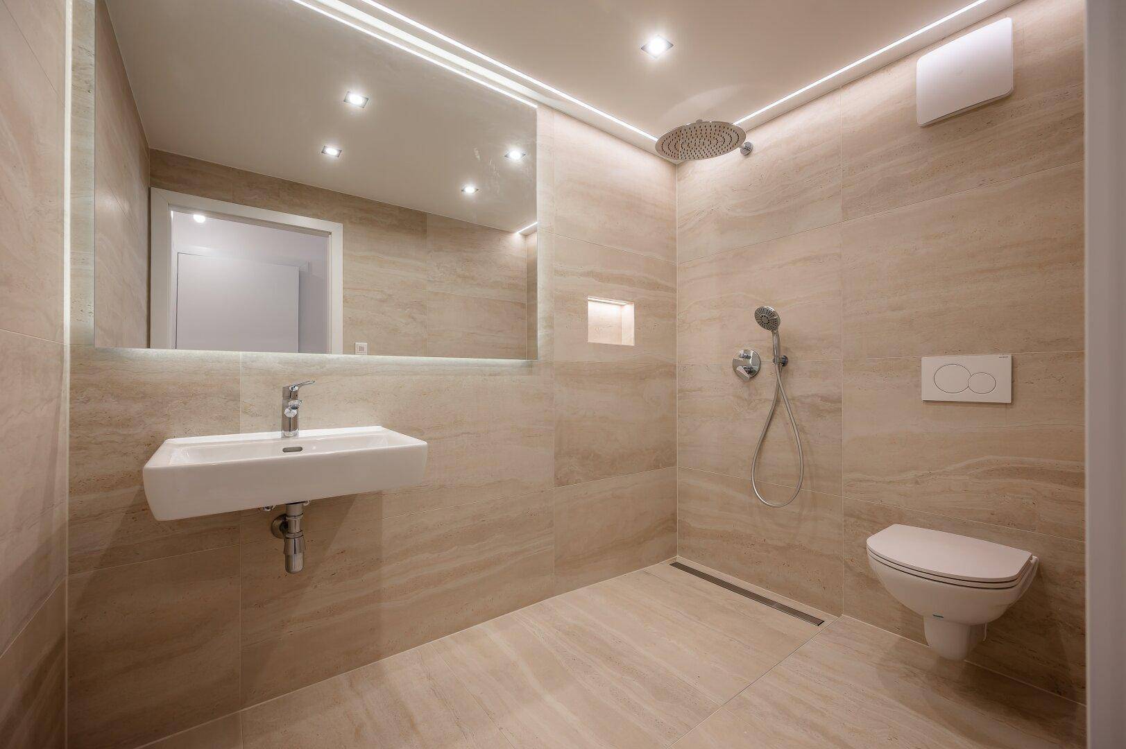 Modernes Badezimmer mit beigefarbenen Fliesen, ebenerdiger Dusche und Wand-WC.
