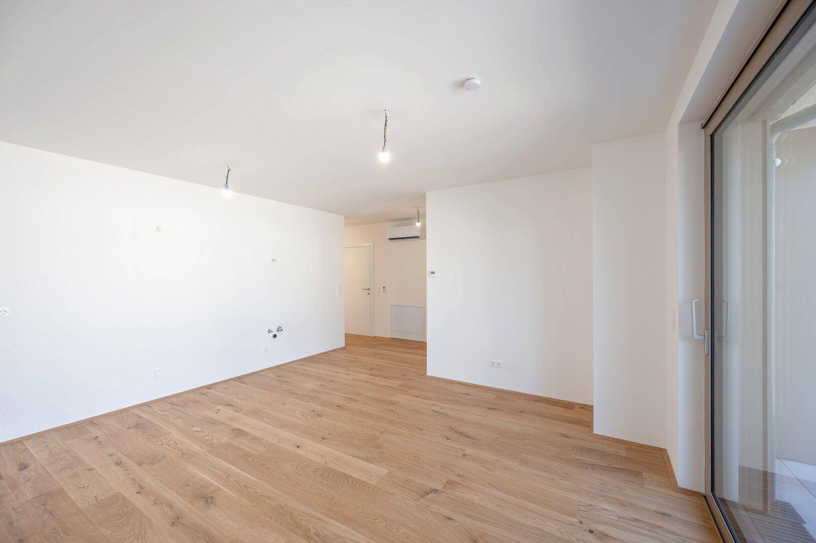 Geräumiger, heller Wohnbereich mit Holzboden und moderner Klimaanlage.