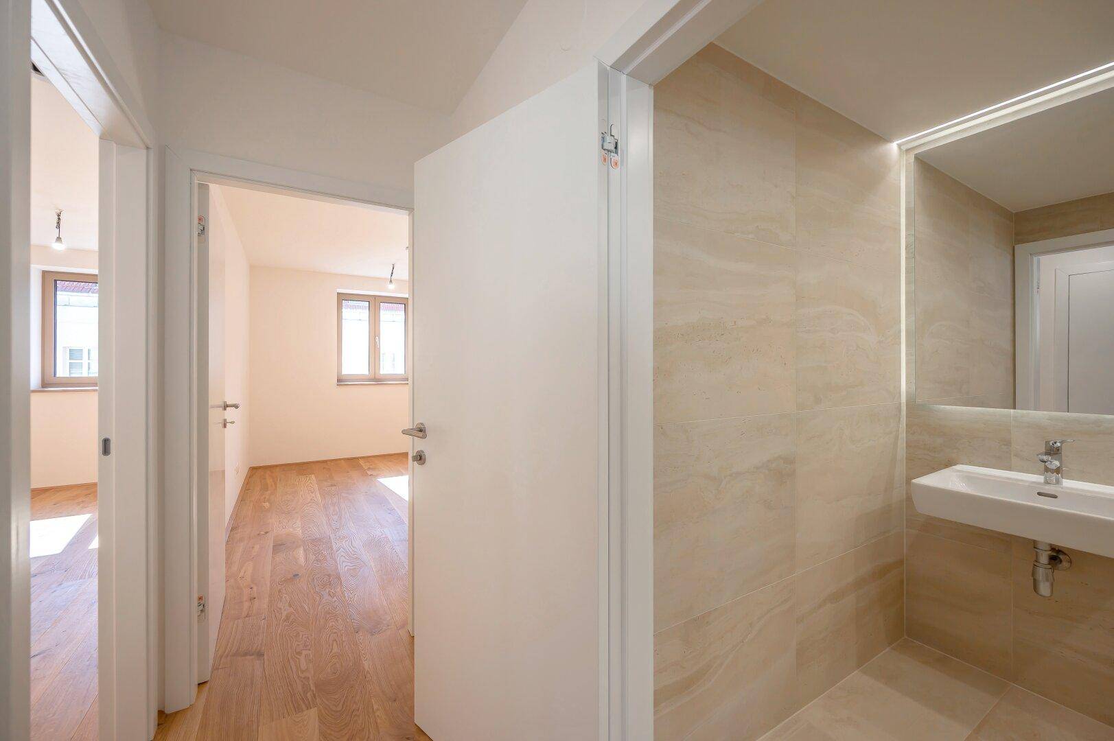 Heller Flur mit Holzboden, der zu den Schlafzimmern und dem modernen Badezimmer führt.
