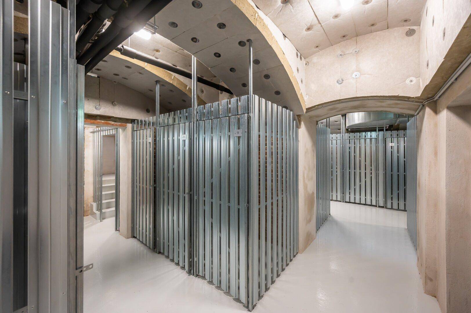Kellerabteile mit Metallwänden und Betonboden, bieten zusätzlichen Stauraum.