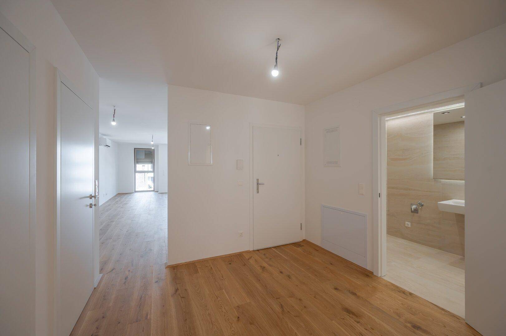 Heller Flur mit Holzboden und direktem Zugang zu einem modernen Badezimmer.
