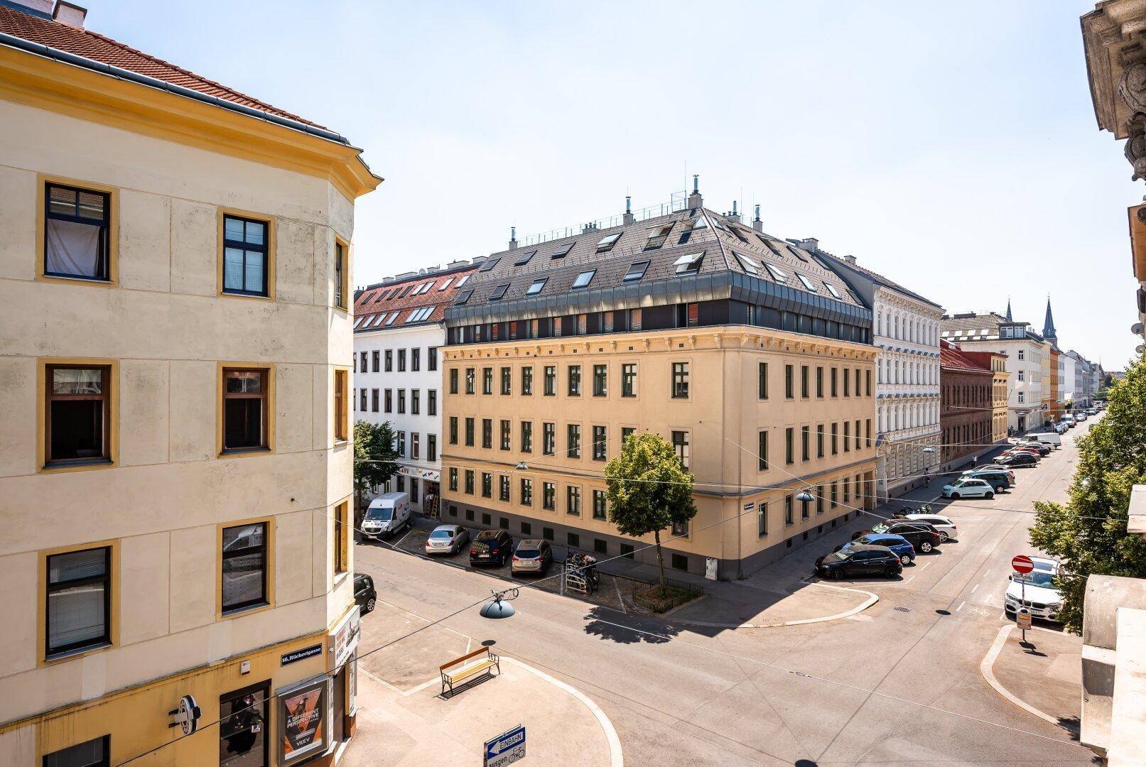 Panoramablick auf eine belebte Stadtstraße mit historischen Gebäuden unter blauem Himmel.