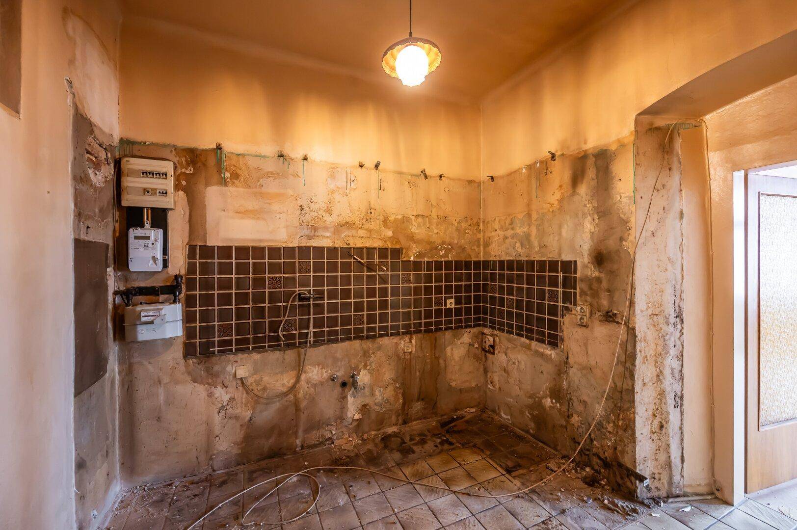Küche im Rohzustand mit Fliesenrückwand und freiliegenden Wänden, bereit für den Einbau einer neuen Küche.