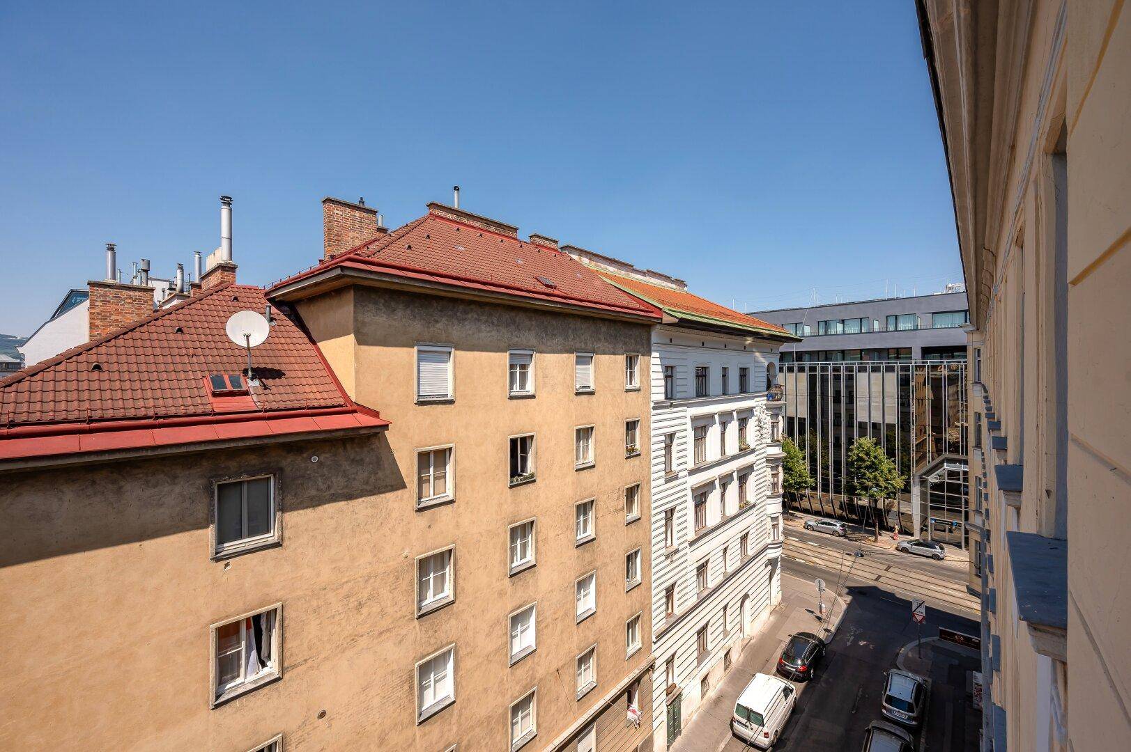 Blick auf die Dächer und Fassaden von Altbauten in einer belebten Stadtlandschaft.