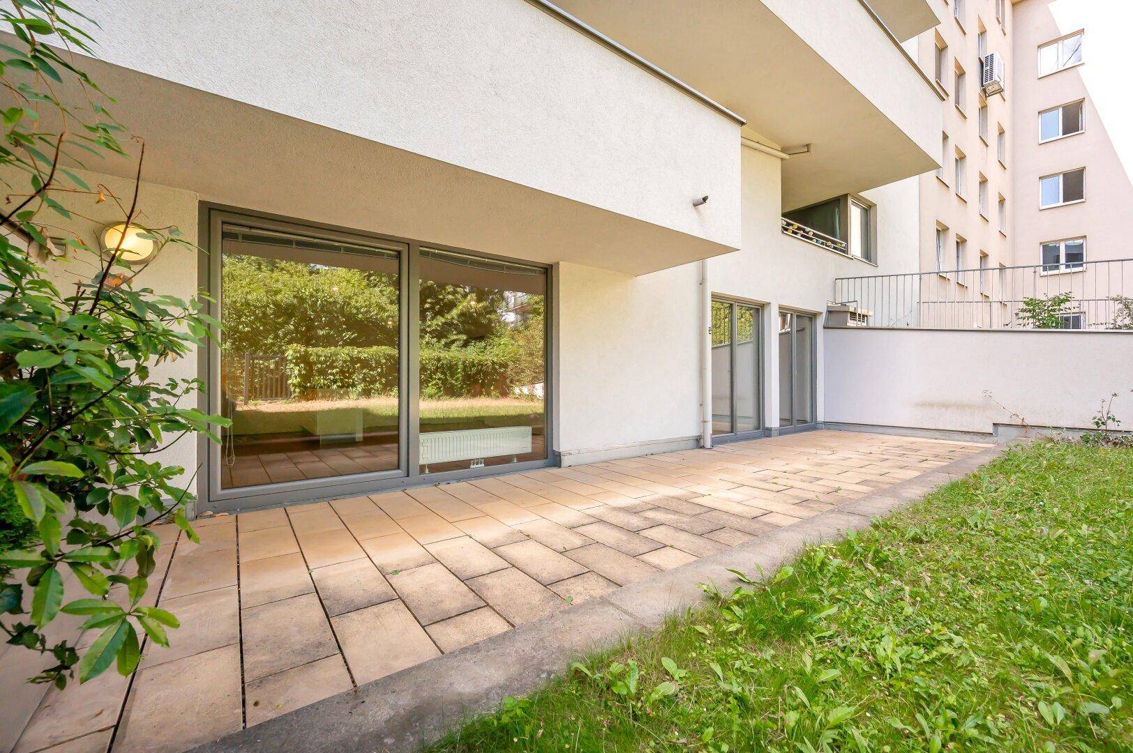 Große, gepflasterte Terrasse mit Zugang zu den Innenräumen durch bodentiefe Fenster.