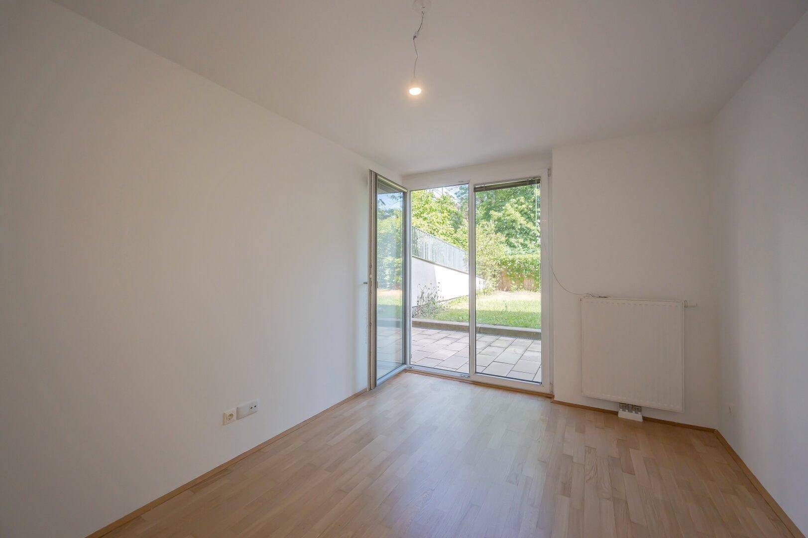 Helles Zimmer mit Parkettboden und direktem Zugang zur Terrasse und zum Garten.