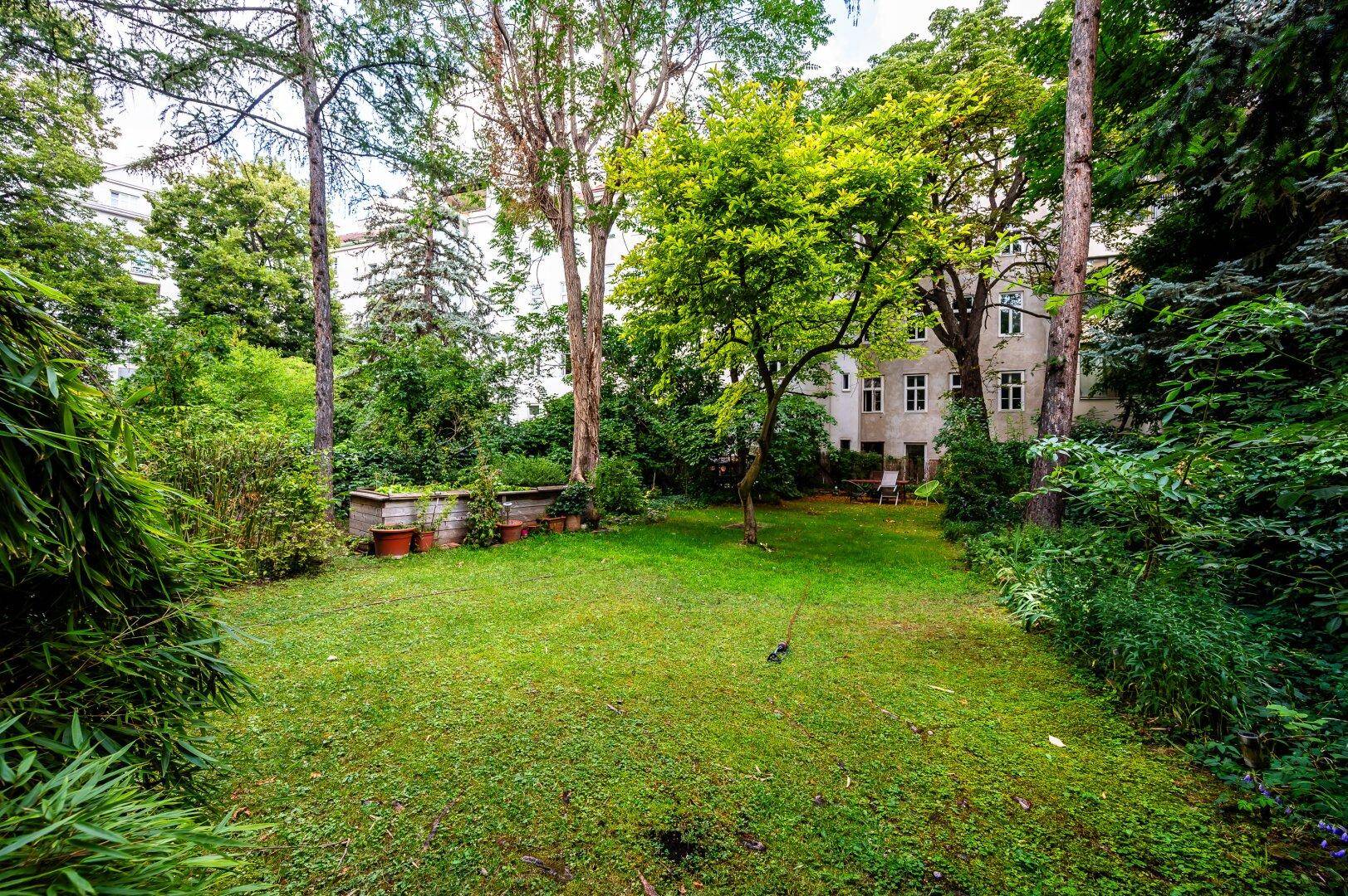 Großer Gemeinschaftsgarten mit gepflegtem Rasen und altem Baumbestand.