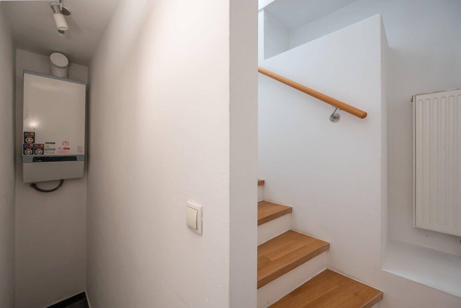 Technikraum mit Heizungsanlage und Zugang zu einer Treppe.