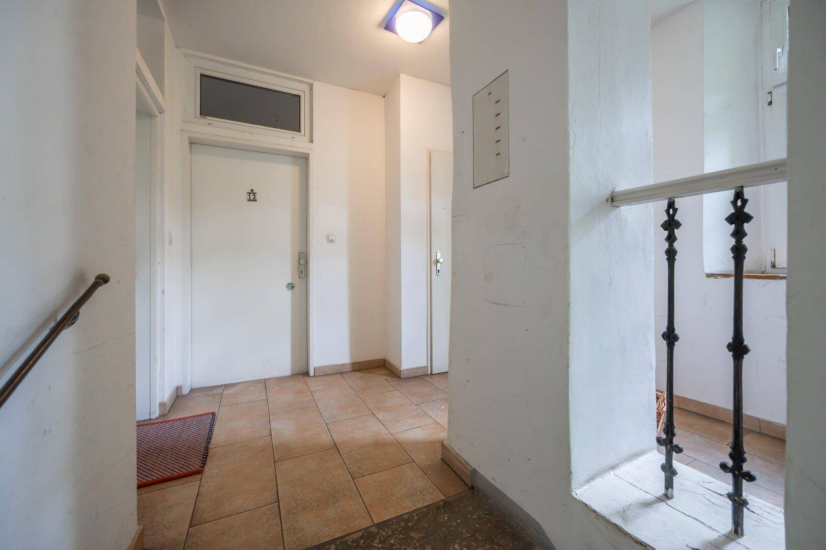 Eingangsbereich eines Mehrfamilienhauses mit Fliesenboden und Zugang zu den Wohnungen.