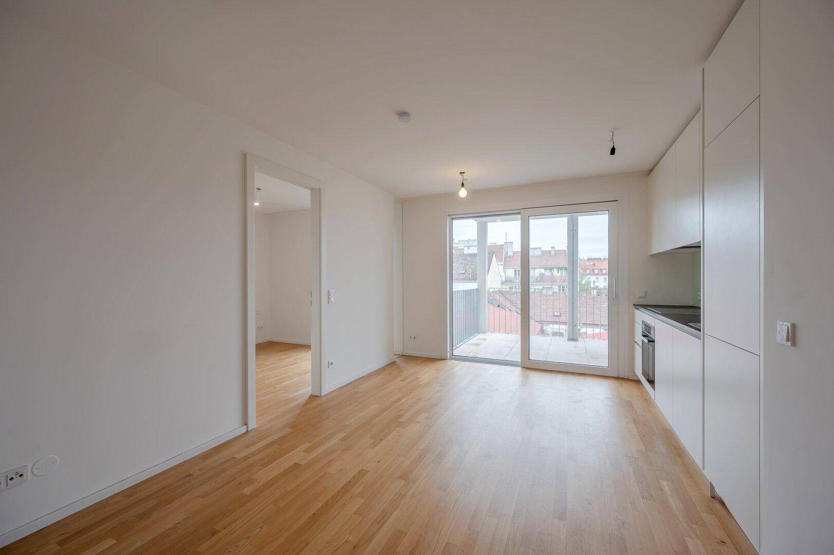 Geräumiger, heller Wohnbereich mit Holzboden und großen Fenstern, ideal als Wohn- oder Schlafzimmer.