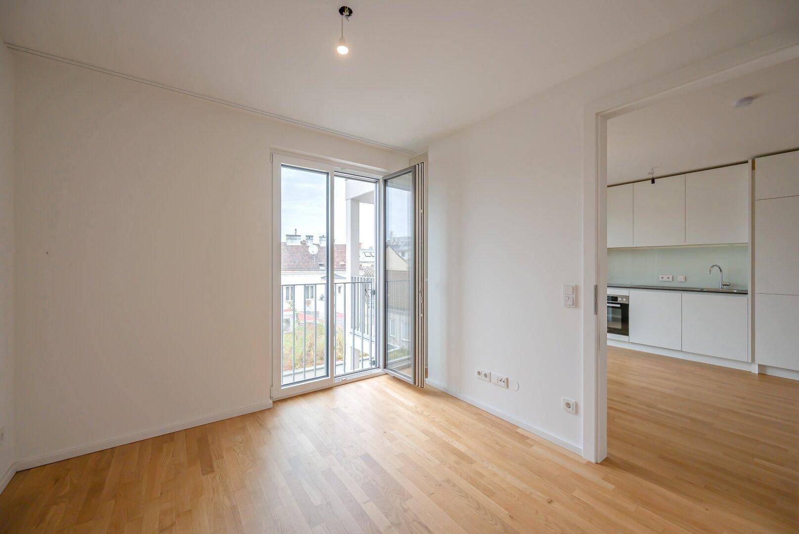 Helles Schlafzimmer mit Holzboden und Zugang zu einem französischen Balkon.