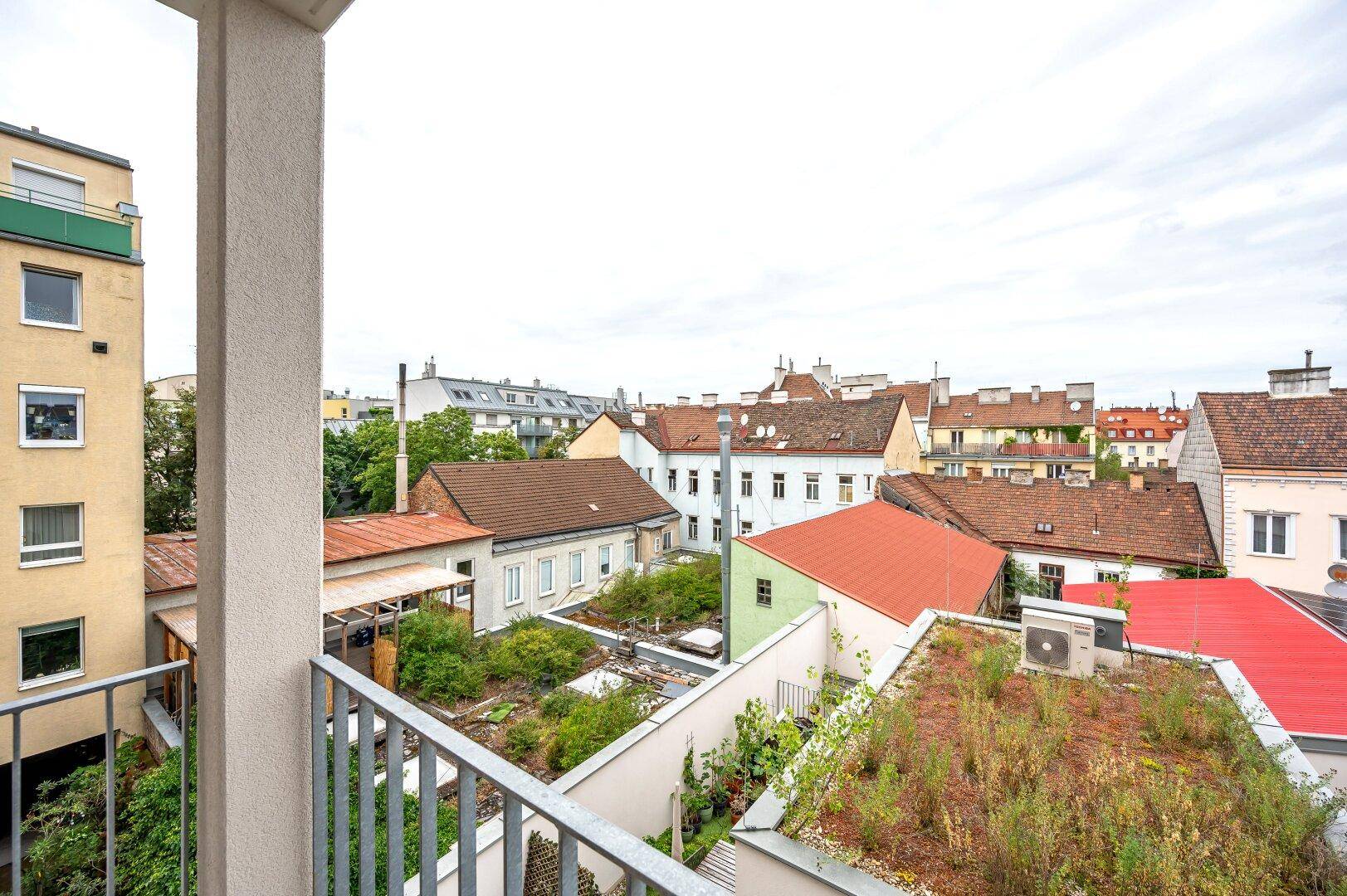 Balkon mit Blick auf begrünte Dächer und die umliegende Stadtlandschaft.