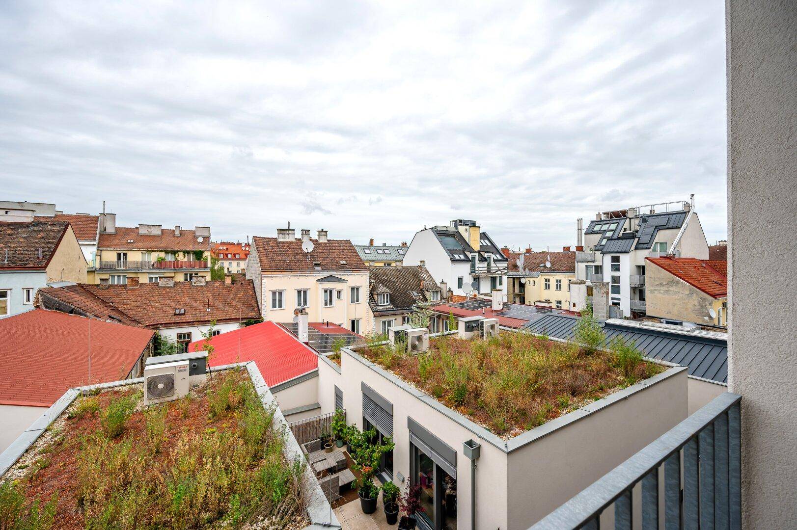 Balkon mit weitem Blick über die Dächer der Stadt und begrünte Flachdächer.