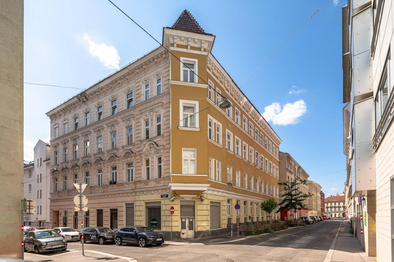 Historisches Eckgebäude mit gelber Fassade und traditioneller Architektur an einer städtischen Straße.