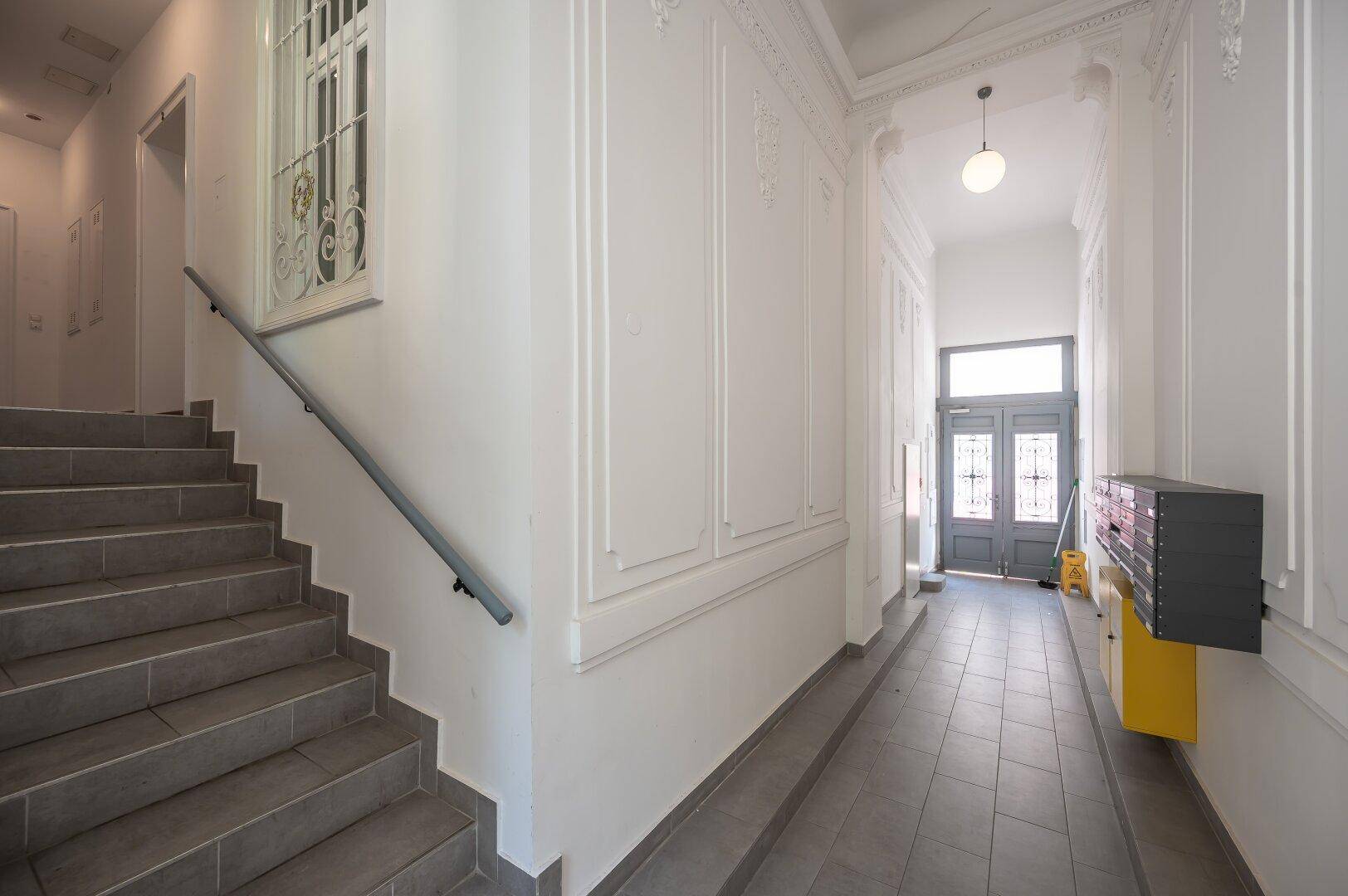 Treppenhaus und Flur im Gemeinschaftsbereich mit dekorativen Wandpaneelen und Briefkästen.