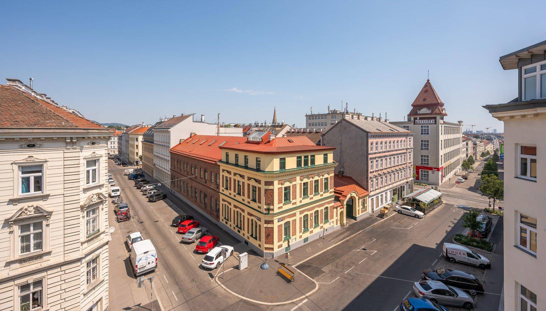Panoramablick über eine belebte Stadtstraße mit historischen Gebäuden und geparkten Autos.