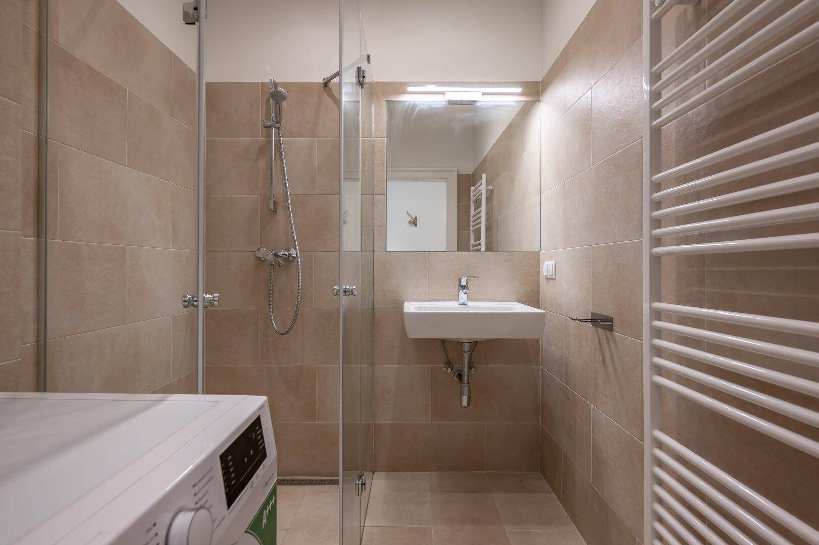 Modernes Badezimmer mit begehbarer Dusche, Waschbecken und Waschmaschine.