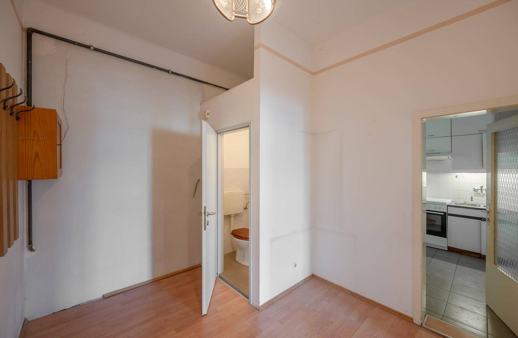 Flur mit Laminatboden, der zu einer kleinen Gästetoilette führt.