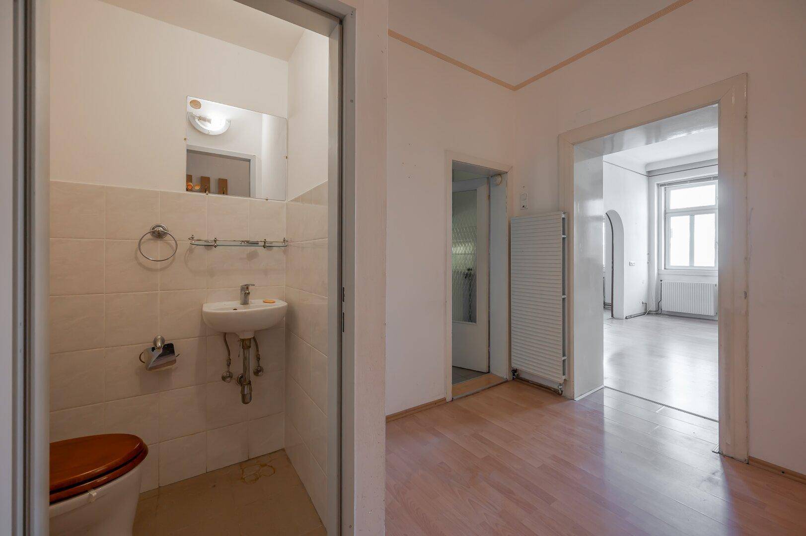 Flur mit Laminatboden, Gästetoilette und separatem Duschbereich.