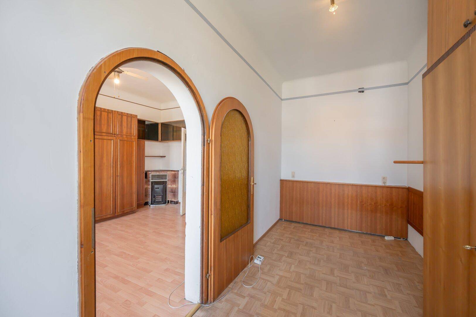 Flur mit Parkettboden, Holzvertäfelung und zwei eleganten Bogentüren.