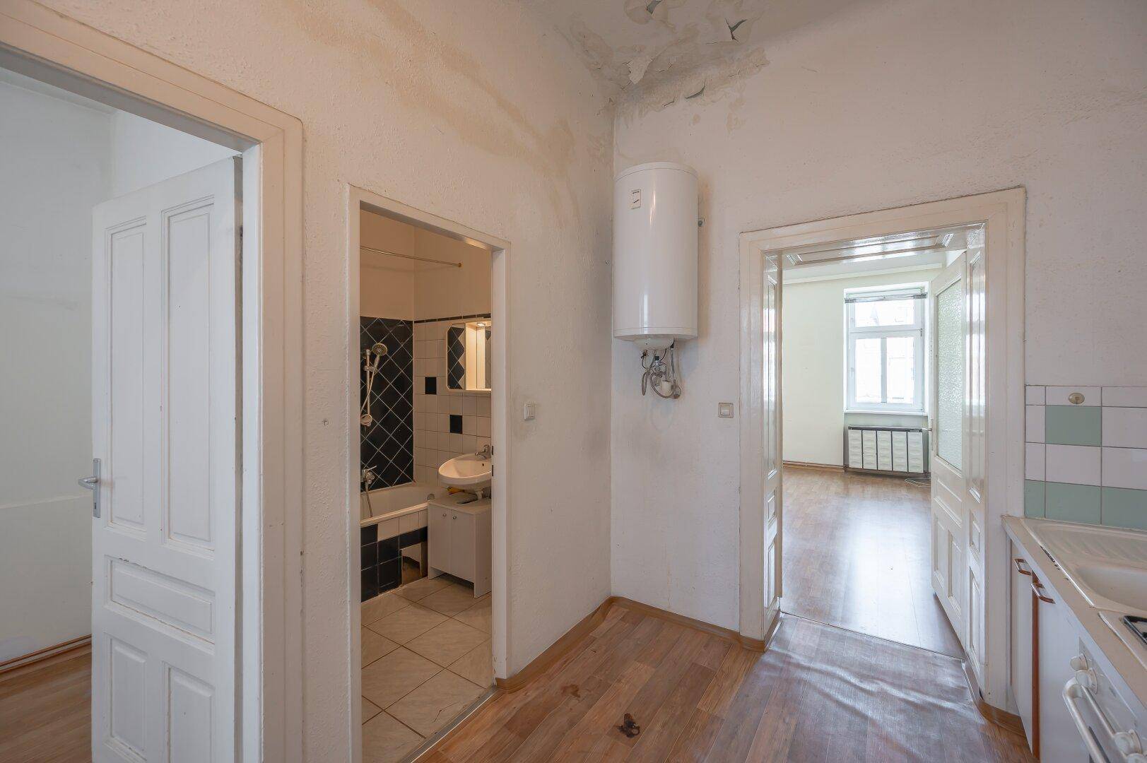 Flur mit Laminatboden, Warmwasserbereiter und Zugängen zu Bad und Küche.