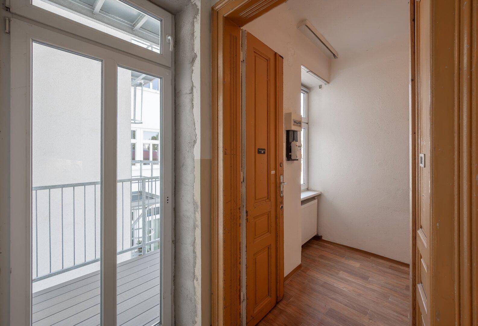 Flur mit Laminatboden und Zugang zu einem Balkon.