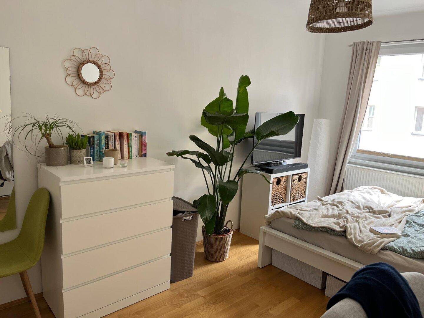 Gemütliches Schlafzimmer mit Kommode, Pflanzen und Blick auf die Umgebung.