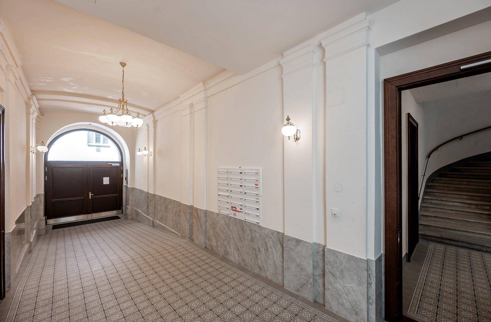 Eleganter Eingangsbereich mit gemusterten Fliesen, Marmorverkleidung und historischem Charme.
