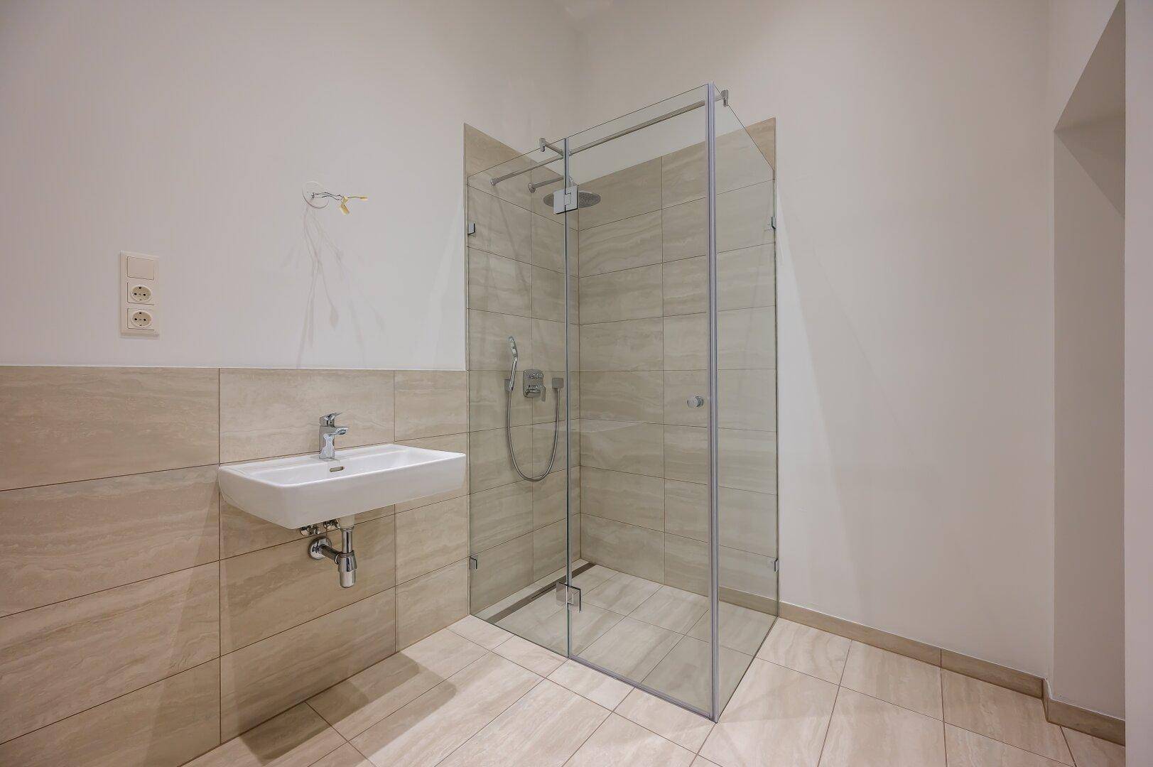 Modernes Badezimmer mit geräumiger Glasdusche und elegantem Waschbecken.